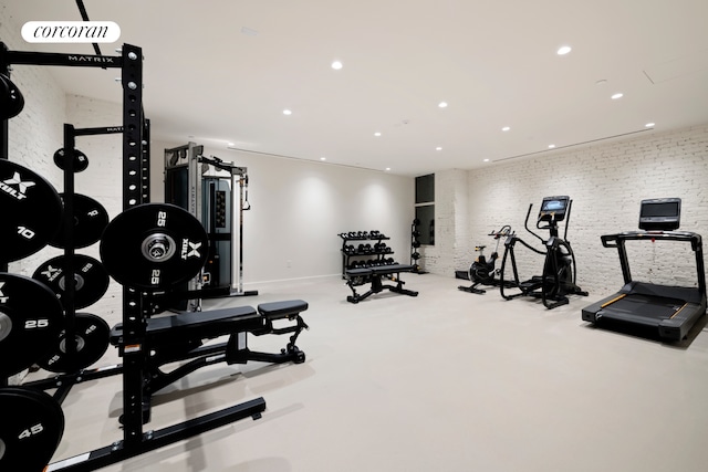 workout area featuring recessed lighting, brick wall, and baseboards