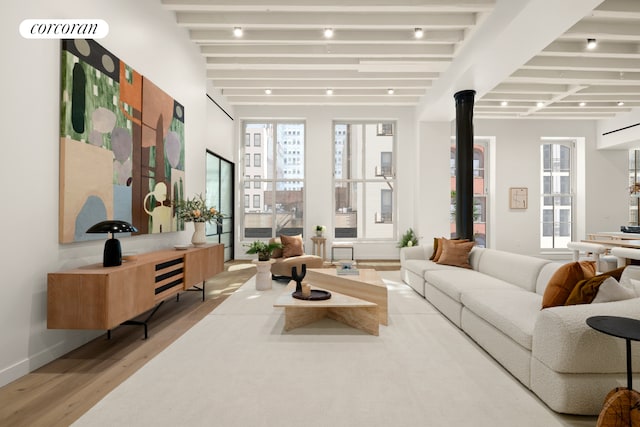 living area with beam ceiling, baseboards, and wood finished floors