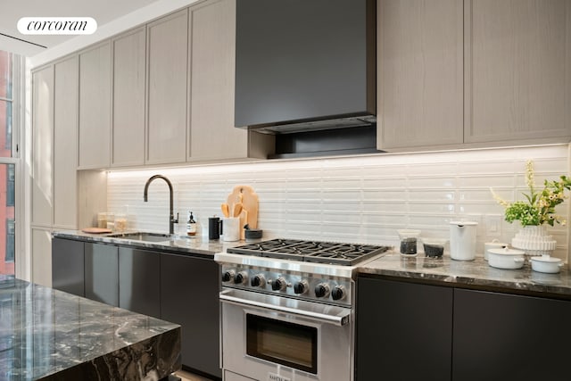 kitchen with stainless steel stove, a sink, decorative backsplash, and wall chimney exhaust hood