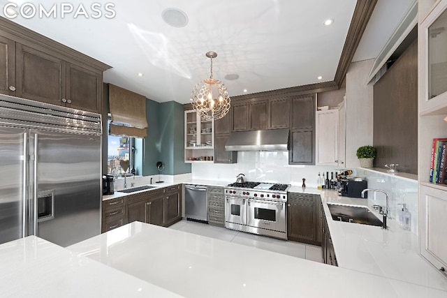 kitchen featuring pendant lighting, sink, premium appliances, and dark brown cabinets