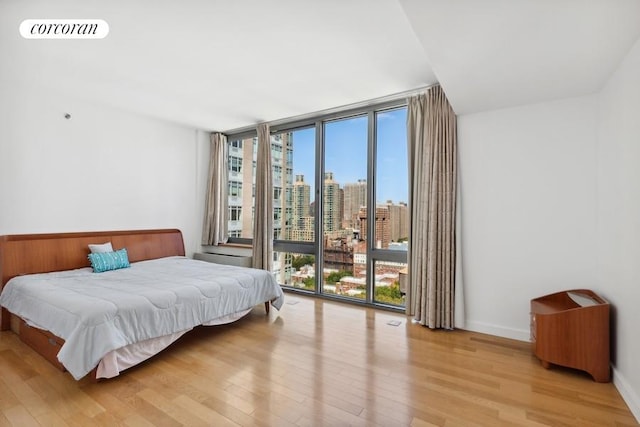 bedroom featuring access to exterior, a wall of windows, and light hardwood / wood-style floors