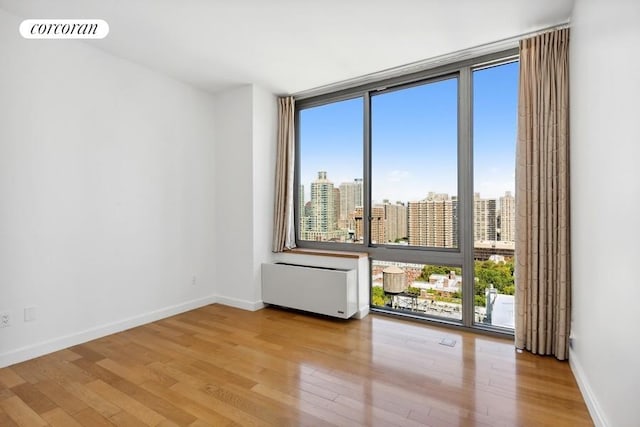 unfurnished room featuring radiator, a wall of windows, and light wood-type flooring