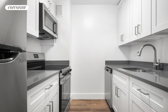 kitchen with dark wood-type flooring, sink, white cabinetry, and stainless steel appliances