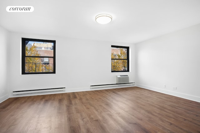 spare room featuring a baseboard radiator, an AC wall unit, visible vents, and wood finished floors