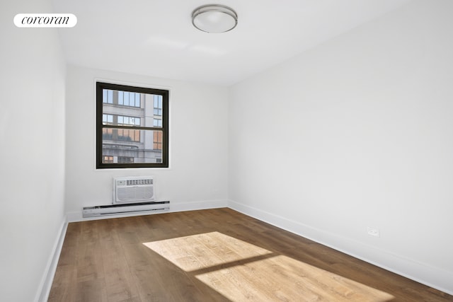 empty room featuring a wall unit AC, visible vents, baseboard heating, wood finished floors, and baseboards