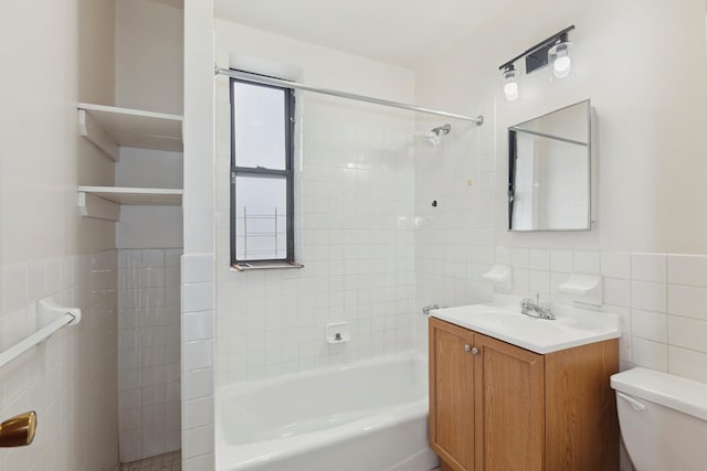 bathroom with vanity, toilet, tile walls, shower / tub combination, and a wainscoted wall