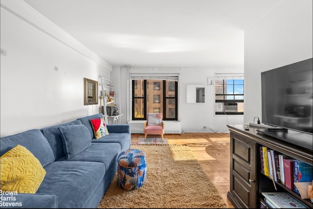 living room with radiator heating unit, light wood-type flooring, and cooling unit