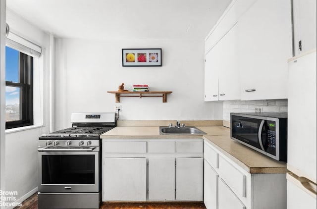 kitchen with appliances with stainless steel finishes, light countertops, white cabinetry, and a sink