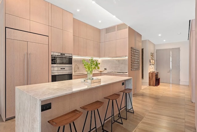 kitchen with light stone countertops, light brown cabinets, paneled refrigerator, and a center island