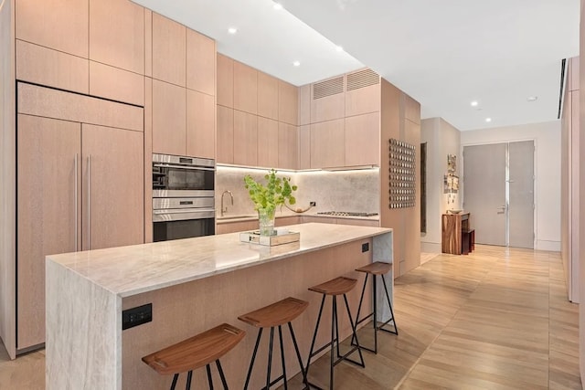 kitchen featuring paneled built in refrigerator, light stone counters, light brown cabinets, and a kitchen island