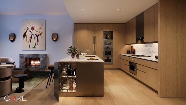 kitchen with a fireplace, decorative backsplash, stainless steel oven, and light hardwood / wood-style floors