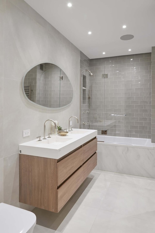 bathroom with toilet, shower / bathtub combination, double vanity, and a sink