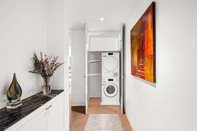 washroom with stacked washing maching and dryer, light wood-style floors, and laundry area