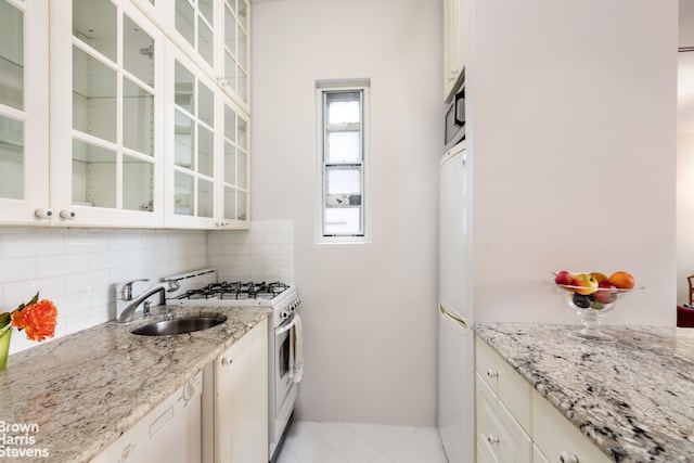405 E 82nd St Unit 2H, New York City, NY 10028 - kitchen featuring white appliances, a sink, decorative backsplash, light stone counters, and glass insert cabinets