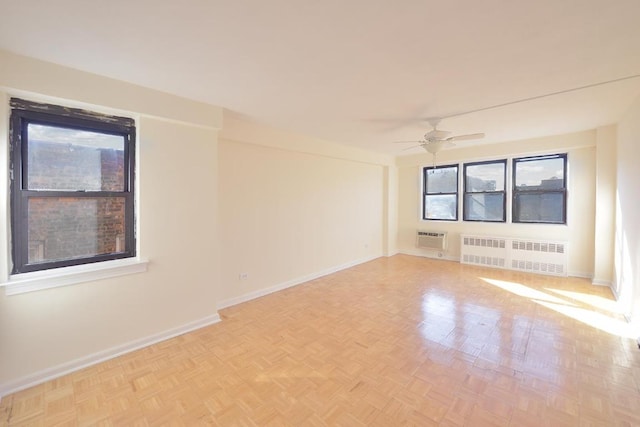 spare room featuring a wall mounted air conditioner, light parquet flooring, ceiling fan, and radiator