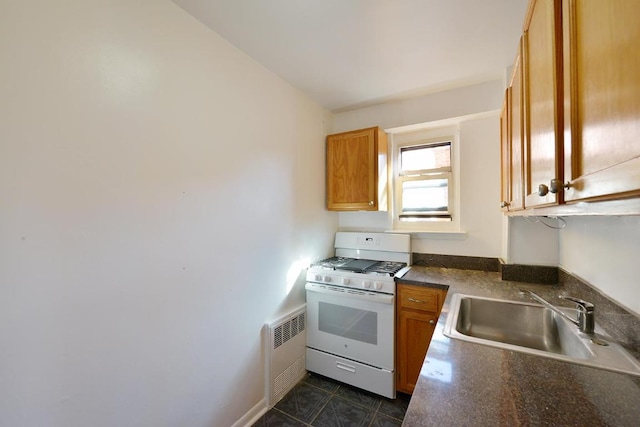 kitchen featuring white range with gas cooktop, sink, radiator heating unit, and dark tile patterned flooring