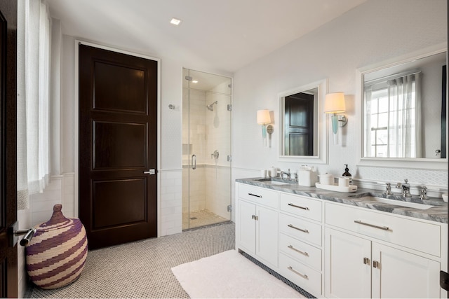 full bathroom with double vanity, a shower stall, and a sink