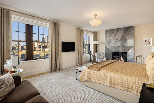 bedroom featuring a chandelier, a fireplace, and baseboards