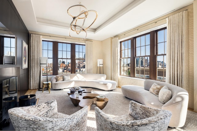 living room featuring a tray ceiling, a view of city, and an inviting chandelier