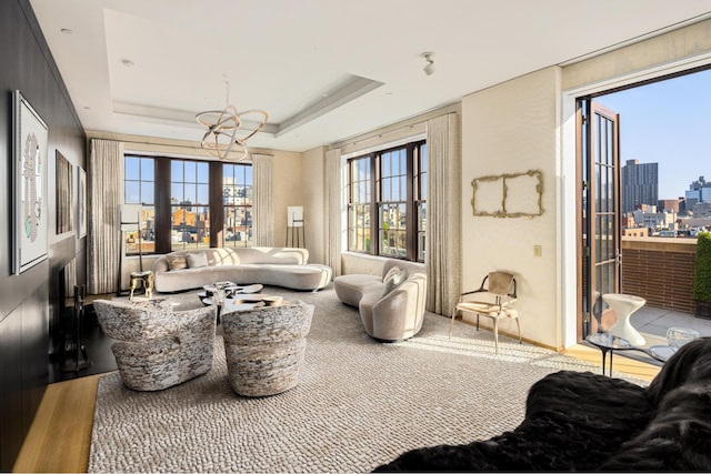 interior space featuring a tray ceiling, a city view, and an inviting chandelier