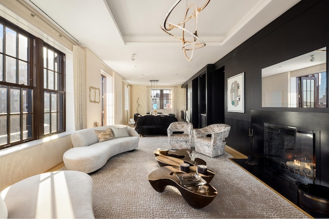 living area featuring a tray ceiling and a glass covered fireplace