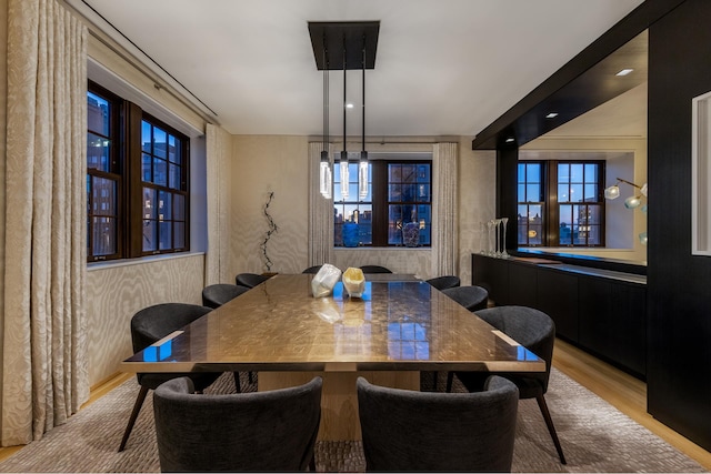 dining space with wallpapered walls and wood finished floors