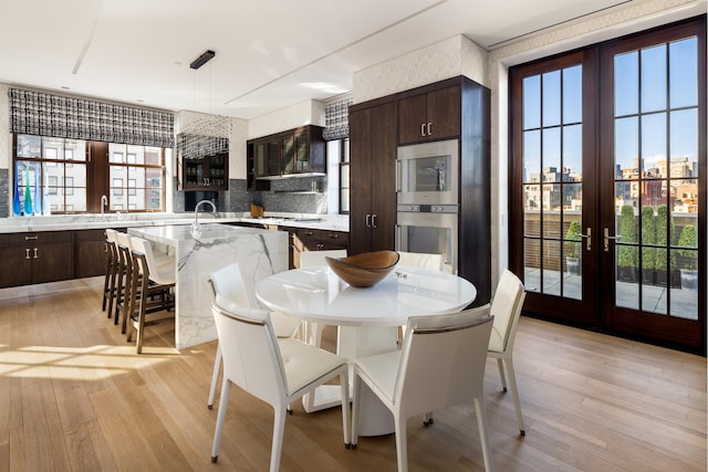 dining space with light wood-type flooring and french doors