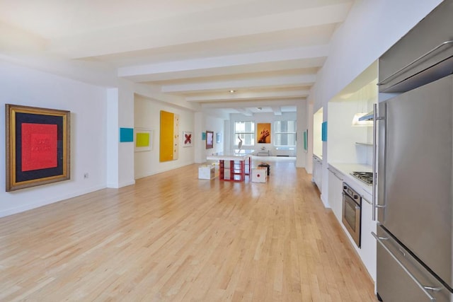 kitchen with hanging light fixtures, appliances with stainless steel finishes, beam ceiling, and light wood-type flooring