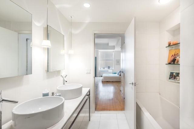 bathroom with a sink, a washtub, double vanity, and tile patterned flooring