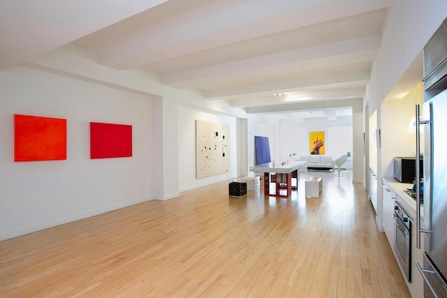 interior space featuring light wood-style flooring, beam ceiling, and baseboards