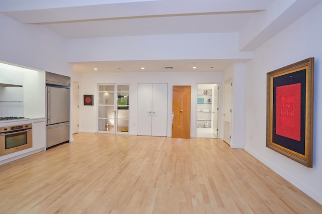 unfurnished living room featuring recessed lighting, light wood-style flooring, and baseboards