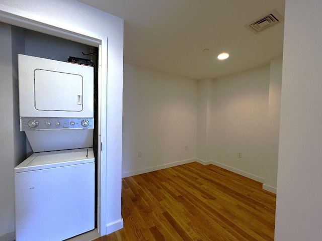 laundry area featuring stacked washer / dryer and hardwood / wood-style floors