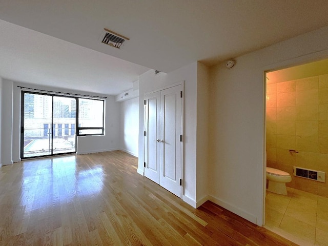 spare room featuring tile walls and light wood-type flooring