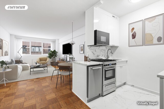 kitchen with sink, appliances with stainless steel finishes, white cabinetry, decorative backsplash, and decorative light fixtures