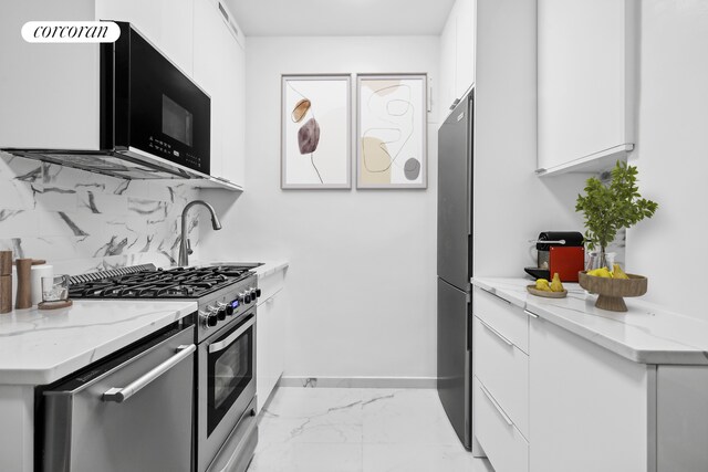 kitchen with sink, white cabinets, backsplash, stainless steel appliances, and light stone countertops