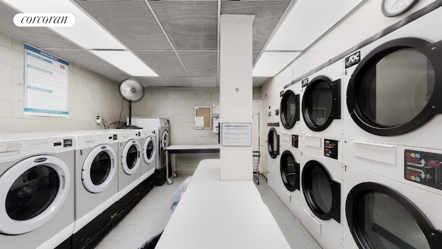 shared laundry area featuring concrete block wall, washing machine and dryer, visible vents, and stacked washer / dryer