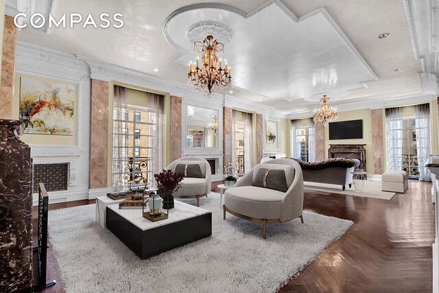 living room featuring an inviting chandelier, parquet flooring, ornamental molding, and plenty of natural light