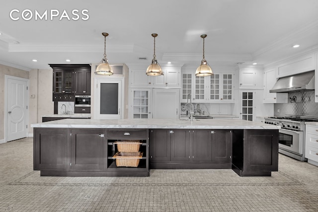 kitchen featuring a large island with sink, stainless steel appliances, white cabinetry, wall chimney exhaust hood, and a sink