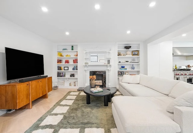 living room with a premium fireplace, built in features, and light parquet floors