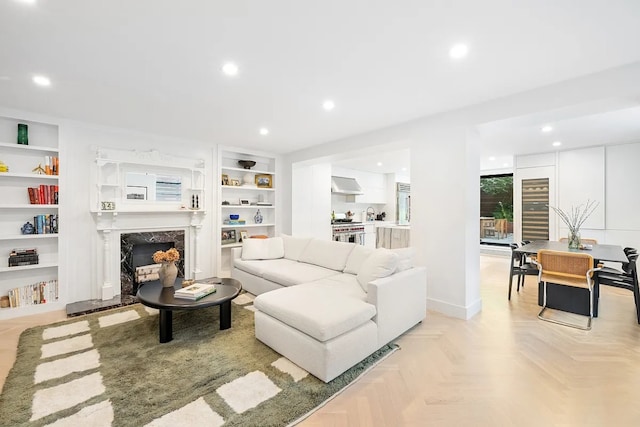 living room featuring built in shelves, light parquet flooring, and a premium fireplace