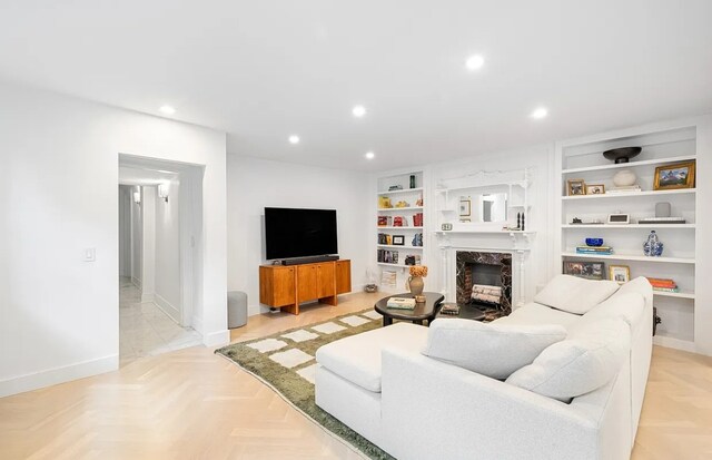 living room with light parquet floors, a high end fireplace, and built in shelves