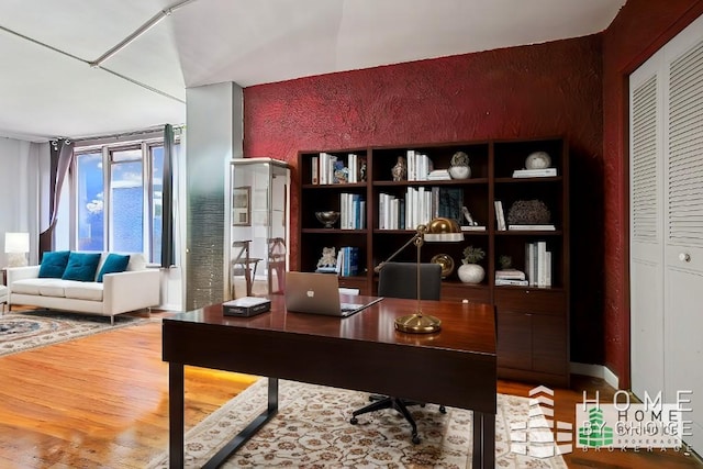 home office with wood-type flooring and expansive windows