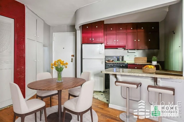 kitchen featuring range, white fridge, and light hardwood / wood-style flooring