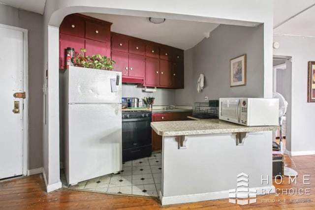 kitchen featuring sink, range, refrigerator, a kitchen bar, and kitchen peninsula