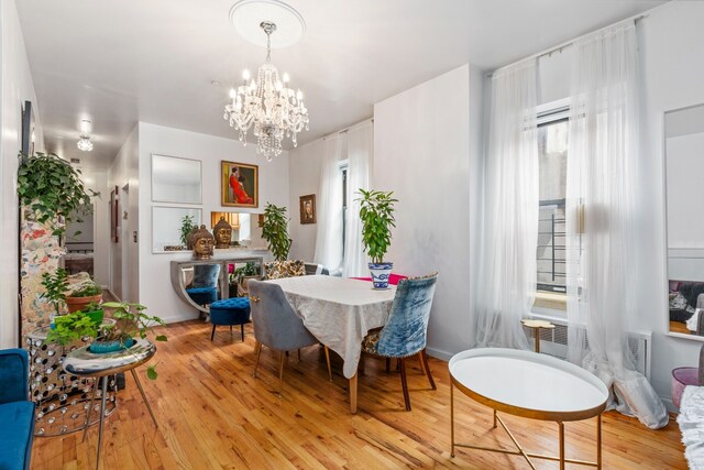 dining space featuring light wood-type flooring and a chandelier