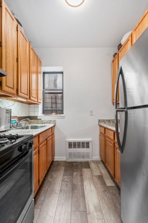 kitchen featuring tasteful backsplash, stainless steel appliances, sink, and light hardwood / wood-style floors