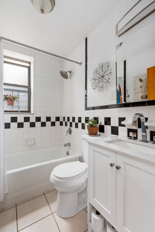 full bathroom with tile patterned floors, toilet, tile walls, vanity, and tiled shower / bath combo