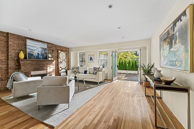 living room featuring a brick fireplace, brick wall, and light hardwood / wood-style flooring