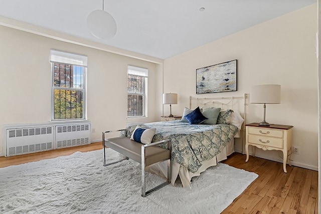 bedroom featuring baseboards, wood finished floors, and radiator