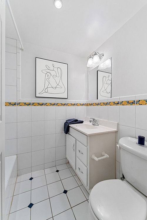 full bath featuring vanity, toilet, tile patterned flooring, and tile walls